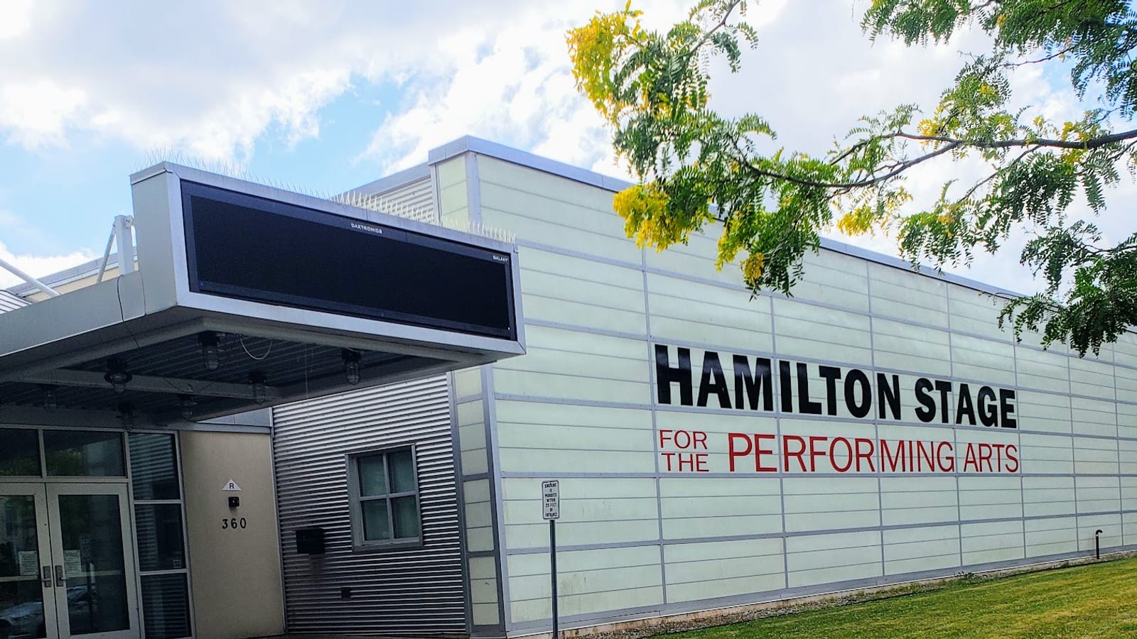 The pale grey front of the Hamilton Stage for the Performing Arts in Rahway, with its name in black and red letters beside a glass entrance.
